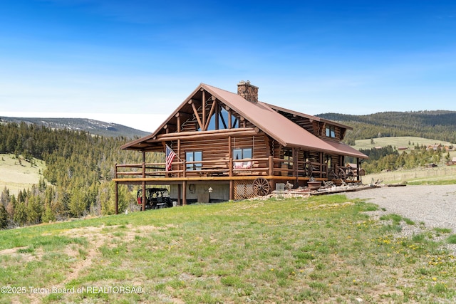 196 Soda Springs Dr, Dubois, WY 82513 - rear view of property featuring a chimney, a deck with mountain view, log exterior, and a wooded view