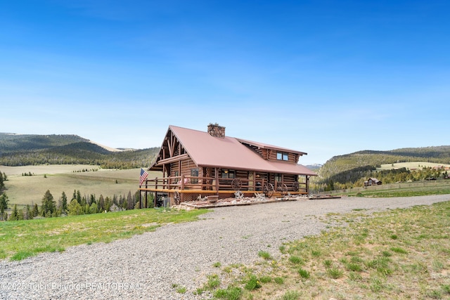 196 Soda Springs Dr, Dubois, WY 82513 - view of front facade featuring log siding, a mountain view, a chimney, and a metal roof