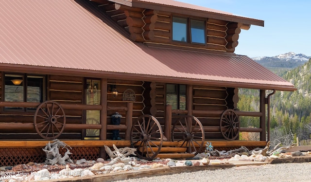 196 Soda Springs Dr, Dubois, WY 82513 - view of front facade featuring log exterior, a porch, a metal roof, and a mountain view