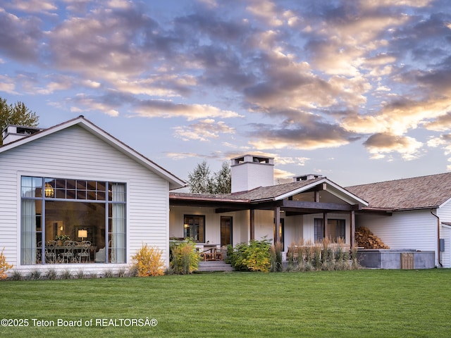 5025 Shoshone Dr, Wilson, WY 83014 - back of property at dusk with a chimney, a yard, and a porch