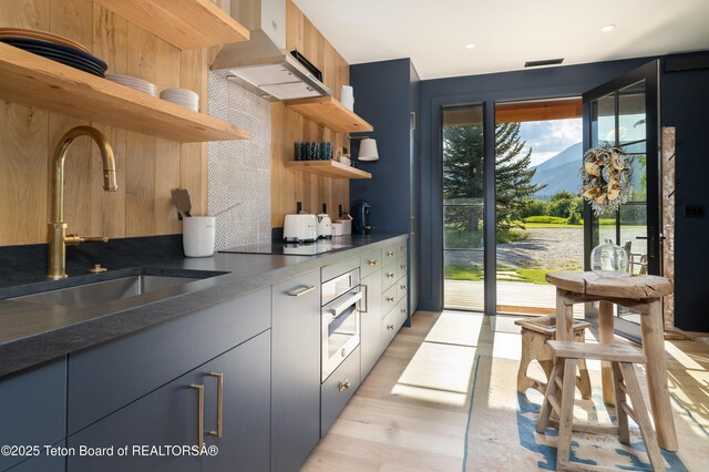 5025 Shoshone Dr, Wilson, WY 83014 - kitchen with open shelves, ventilation hood, decorative backsplash, stovetop, and oven