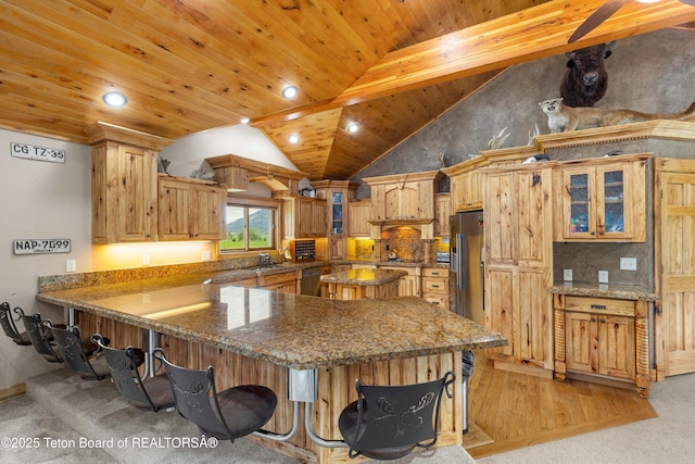 1255 Lost Crk, Thayne, WY 83127 - kitchen with a breakfast bar, a peninsula, lofted ceiling, glass insert cabinets, and dark stone countertops