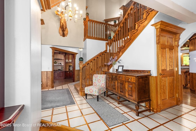 1255 Lost Crk, Thayne, WY 83127 - staircase featuring a chandelier, a wainscoted wall, a high ceiling, and wooden walls