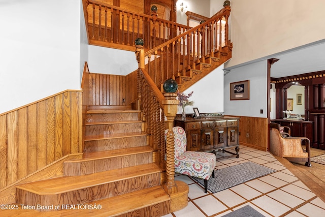 1255 Lost Crk, Thayne, WY 83127 - stairs featuring wooden walls, wainscoting, a towering ceiling, and tile patterned flooring