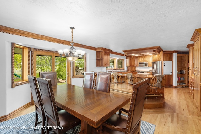 1255 Lost Crk, Thayne, WY 83127 - dining room with a chandelier, baseboards, crown molding, a textured ceiling, and light wood finished floors