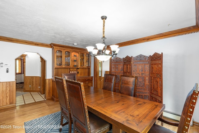 1255 Lost Crk, Thayne, WY 83127 - dining area featuring a chandelier, light wood-style floors, a wainscoted wall, crown molding, and arched walkways