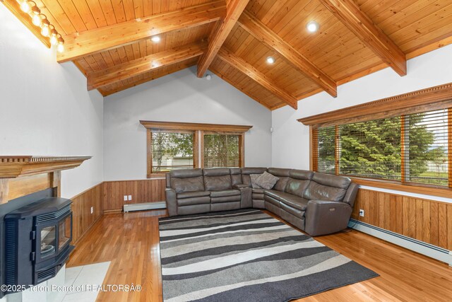 1255 Lost Crk, Thayne, WY 83127 - living room with healthy amount of natural light, a baseboard radiator, a wood stove, wainscoting, and wooden ceiling