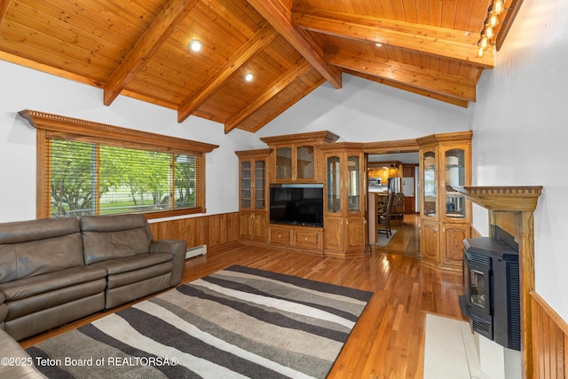 1255 Lost Crk, Thayne, WY 83127 - living room featuring wood-type flooring, a wood stove, wood ceiling with exposed beams, wainscoting, and a baseboard heating unit
