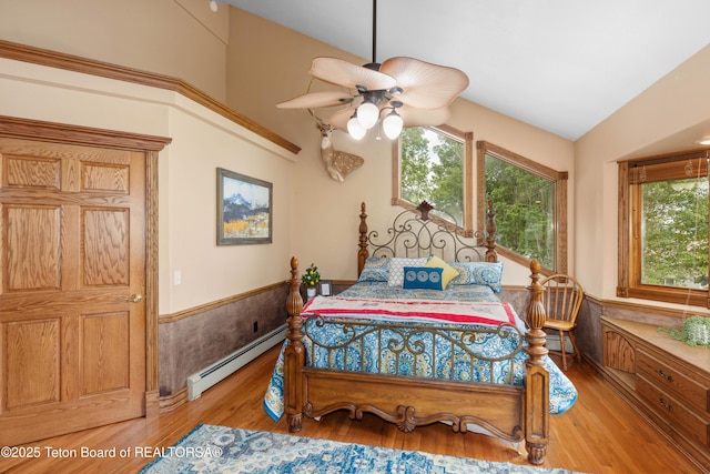 1255 Lost Crk, Thayne, WY 83127 - bedroom with a baseboard radiator, wainscoting, multiple windows, wood finished floors, and vaulted ceiling