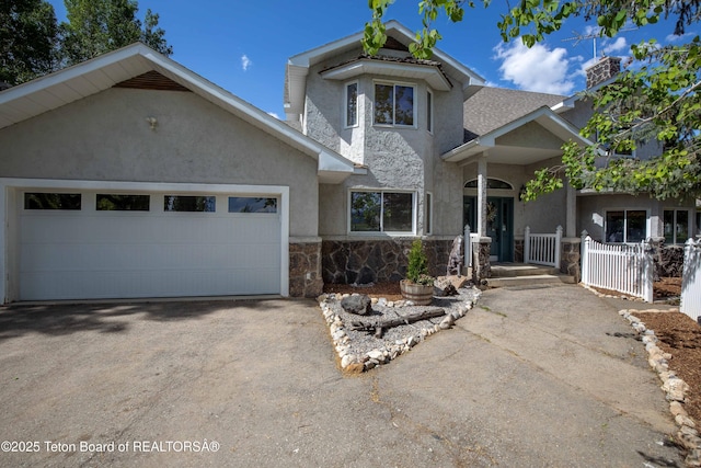 1255 Lost Crk, Thayne, WY 83127 - view of front of property with stone siding, stucco siding, asphalt driveway, an attached garage, and roof with shingles