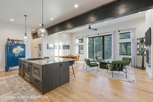5170 Meandering Moose Dr, Victor, ID 83455 - kitchen with light wood-style floors, open floor plan, stainless steel range with gas stovetop, a kitchen breakfast bar, and recessed lighting