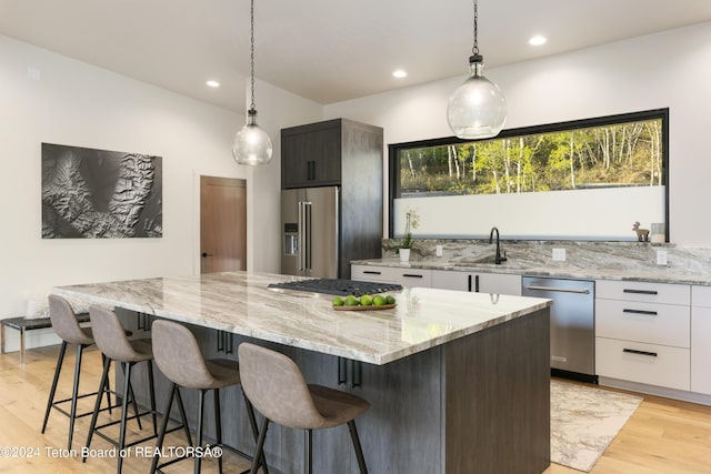 5170 Meandering Moose Dr, Victor, ID 83455 - kitchen with appliances with stainless steel finishes, white cabinetry, light wood finished floors, decorative light fixtures, and a large island