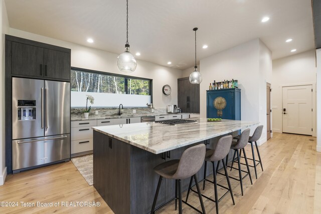 5170 Meandering Moose Dr, Victor, ID 83455 - kitchen with appliances with stainless steel finishes, light wood-type flooring, recessed lighting, a kitchen breakfast bar, and a spacious island