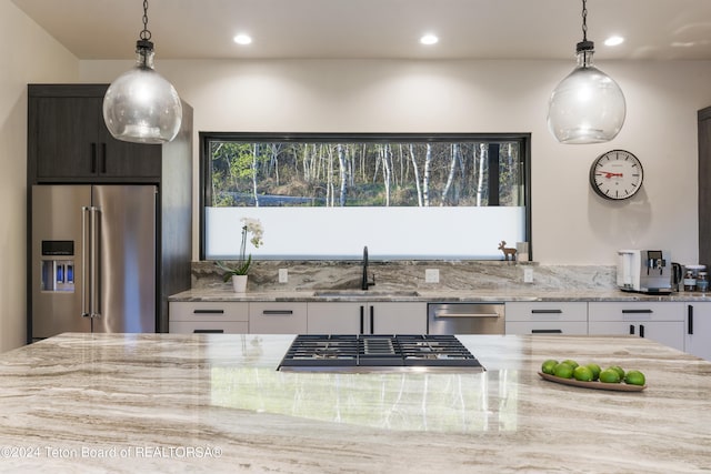 5170 Meandering Moose Dr, Victor, ID 83455 - kitchen with appliances with stainless steel finishes, a sink, white cabinetry, light stone counters, and pendant lighting