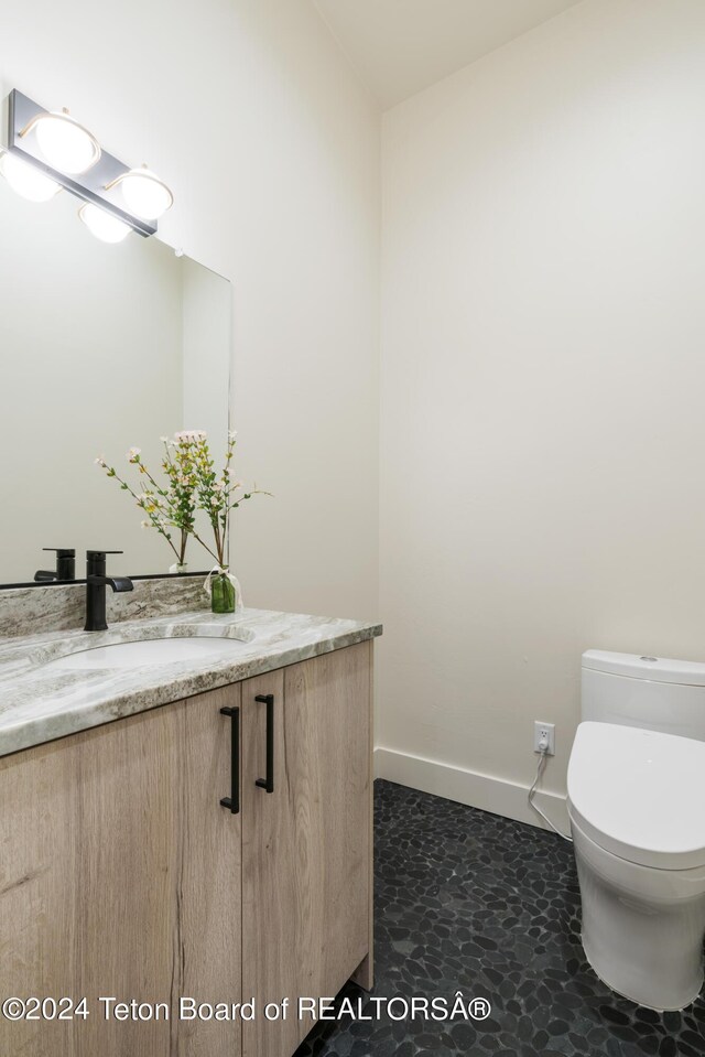 5170 Meandering Moose Dr, Victor, ID 83455 - half bathroom featuring vanity, toilet, and baseboards