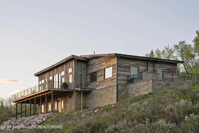 5170 Meandering Moose Dr, Victor, ID 83455 - view of side of home featuring stone siding, a deck, and a balcony