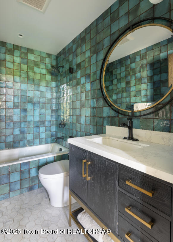 185 S Swan Rd, Jackson, WY 83001 - bathroom with tile walls, vanity, and tiled shower / bath