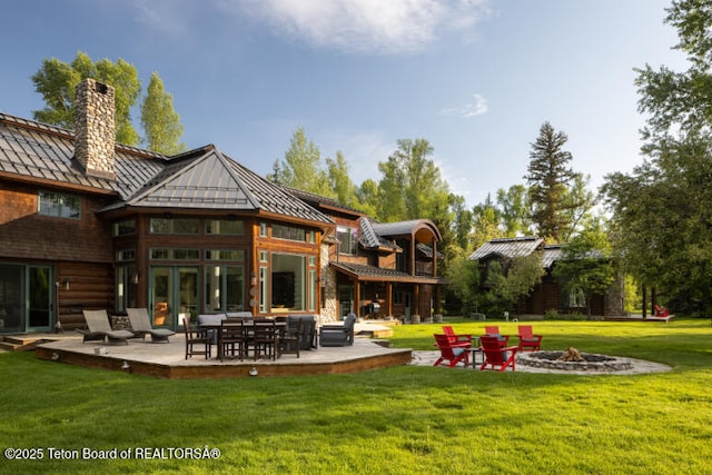 185 S Swan Rd, Jackson, WY 83001 - back of property featuring a standing seam roof, a chimney, an outdoor fire pit, a metal roof, and a yard
