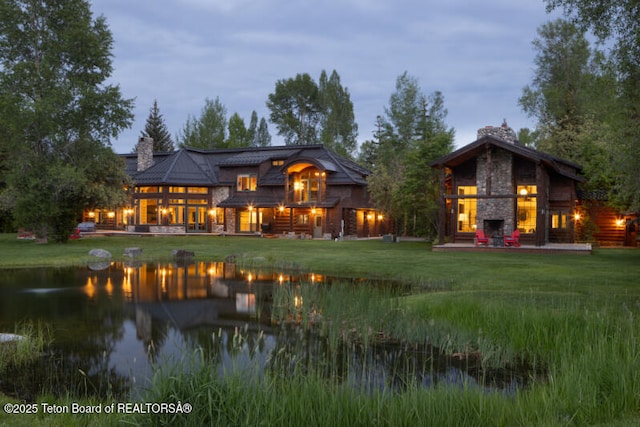 185 S Swan Rd, Jackson, WY 83001 - back of house featuring stone siding, a lawn, a water view, and a chimney