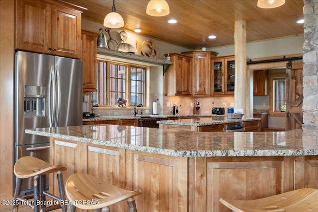 2321 S 3500 W, Driggs, ID 83422 - kitchen with stainless steel refrigerator with ice dispenser, wooden ceiling, brown cabinetry, glass insert cabinets, and light stone counters