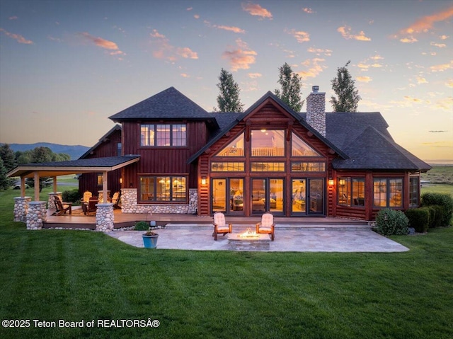 2321 S 3500 W, Driggs, ID 83422 - back of house at dusk with a patio area, a fire pit, a lawn, a chimney, and board and batten siding