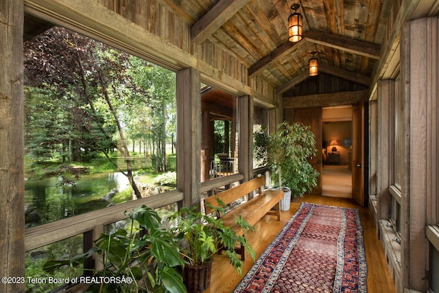 sunroom with lofted ceiling and a water view