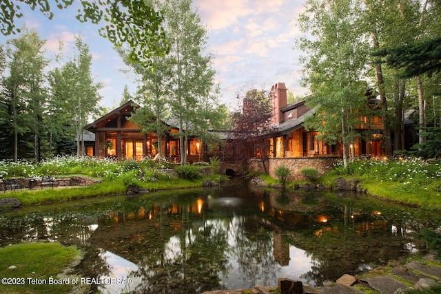 rear view of property with a chimney and a garden pond