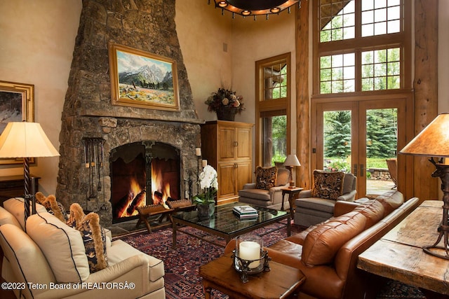 living room featuring a towering ceiling and a stone fireplace
