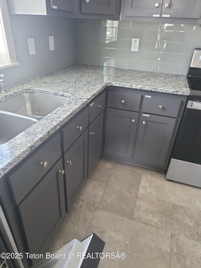360 Wooden Spur Dr, Alpine, WY 83128 - kitchen featuring stainless steel stove, gray cabinets, decorative backsplash, and light stone counters