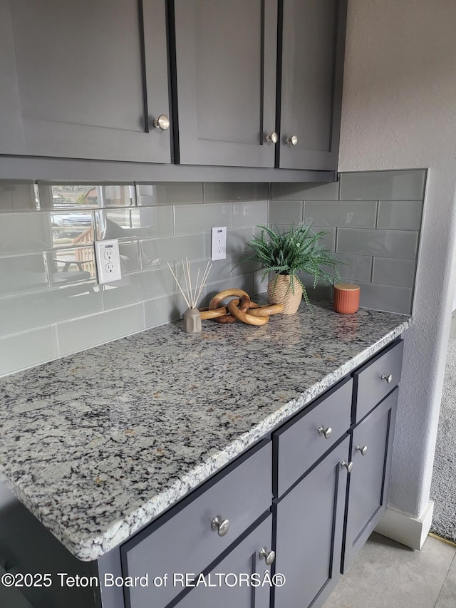 360 Wooden Spur Dr, Alpine, WY 83128 - kitchen with gray cabinetry, tasteful backsplash, light stone counters, and a textured wall
