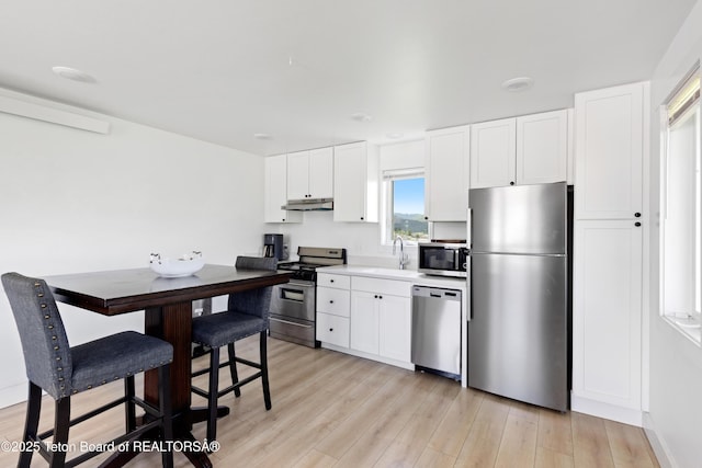 315 Meyers St, Thayne, WY 83127 - kitchen with appliances with stainless steel finishes, under cabinet range hood, light wood finished floors, white cabinets, and light countertops