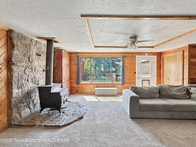 566 Jefferson St, Afton, WY 83110 - living area with a textured ceiling, carpet floors, a wood stove, wooden walls, and ceiling fan