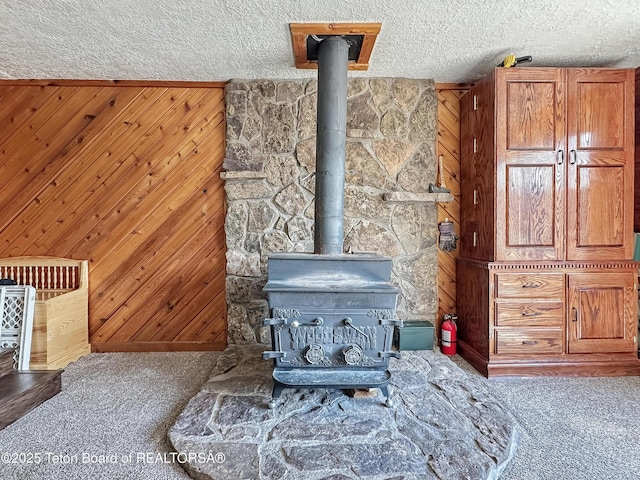 566 Jefferson St, Afton, WY 83110 - detailed view of a wood stove, carpet, a textured ceiling, and wooden walls