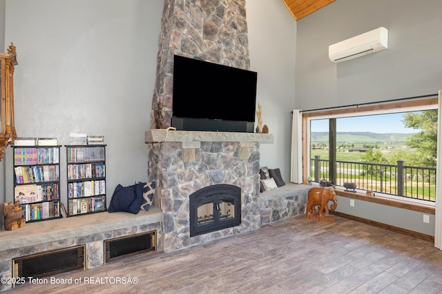 2840 E Dry Crk, Afton, WY 83110 - living area with a wall mounted air conditioner, a stone fireplace, high vaulted ceiling, and wood finished floors