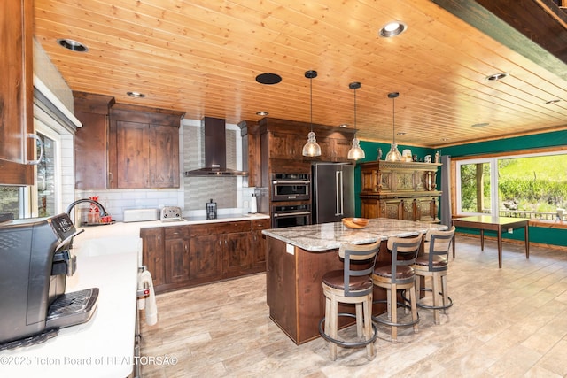 2840 E Dry Crk, Afton, WY 83110 - kitchen featuring wall chimney range hood, stainless steel appliances, light wood-style floors, a center island, and wood ceiling