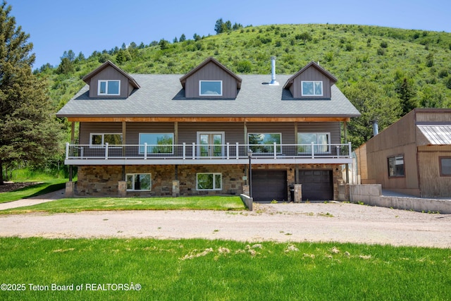2840 E Dry Crk, Afton, WY 83110 - view of front of home featuring driveway, a garage, stone siding, a view of trees, and a front yard