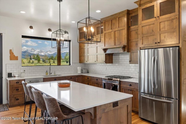 346 S Leigh Ranch Rd, Tetonia, ID 83452 - kitchen with appliances with stainless steel finishes, brown cabinetry, a breakfast bar area, a chandelier, and light countertops