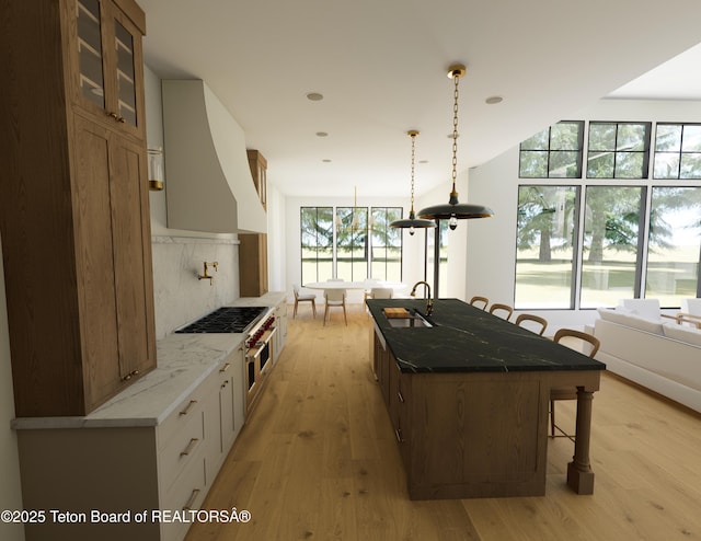 7 Cold Springs Rd, Victor, ID 83455 - kitchen featuring a breakfast bar, light wood-style flooring, light stone counters, glass insert cabinets, and a kitchen island with sink