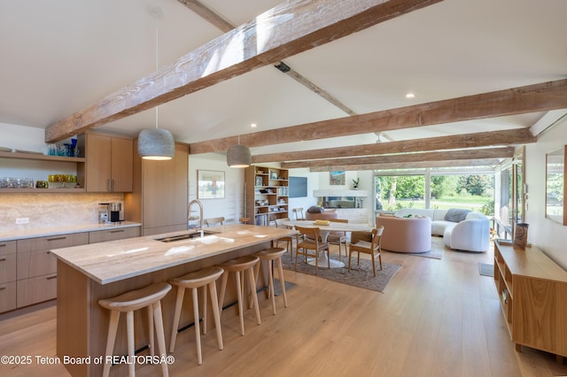 525 E Golf Creek Ln Unit 34, Jackson, WY 83001 - kitchen with beam ceiling, open floor plan, open shelves, an island with sink, and a kitchen bar