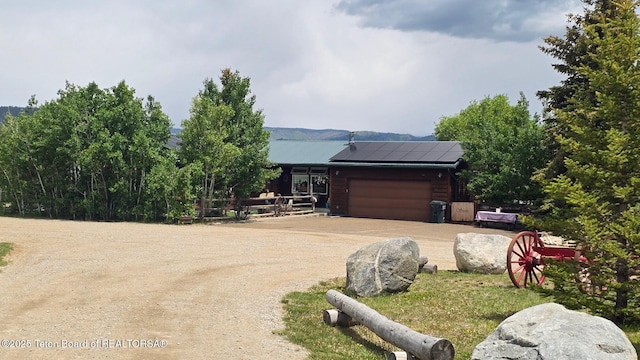 15 E Badger Trl, Pinedale, WY 82941 - view of front facade with dirt driveway, solar panels, and a garage