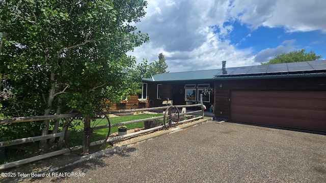 15 E Badger Trl, Pinedale, WY 82941 - view of front of home with a garage, asphalt driveway, solar panels, and a metal roof