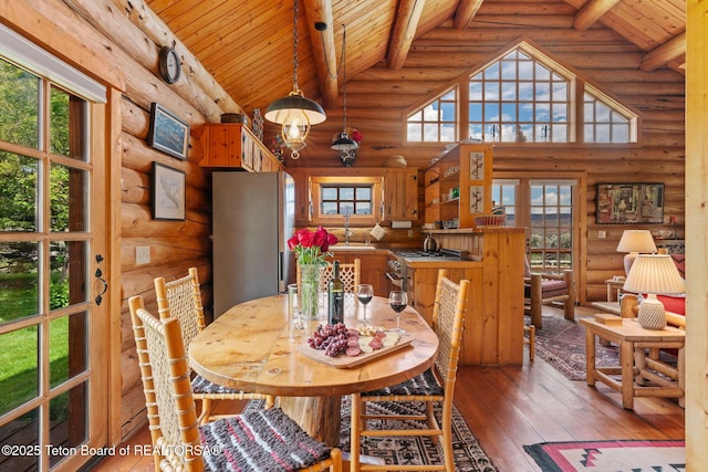 53 Schenck Ln, Dubois, WY 82513 - dining area with log walls, a wood ceiling with exposed beams, wood-type flooring, and high vaulted ceiling