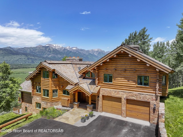 1520 N Pratt Rd, Jackson, WY 83001 - log-style house with stone siding, a garage, driveway, log siding, and a mountain view