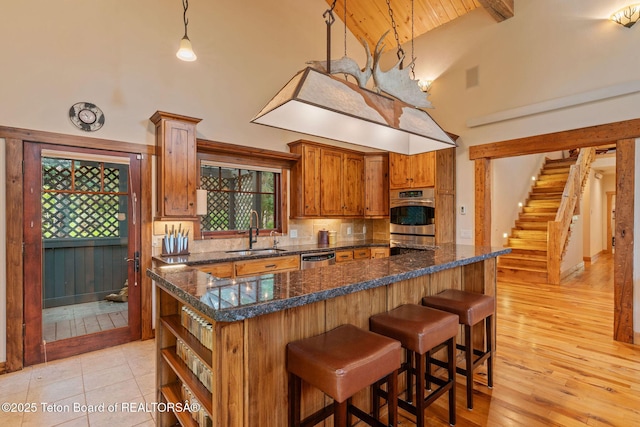 445 Aspen Ridge Trl, Alpine, WY 83128 - kitchen featuring high vaulted ceiling, brown cabinets, open shelves, appliances with stainless steel finishes, and a kitchen bar