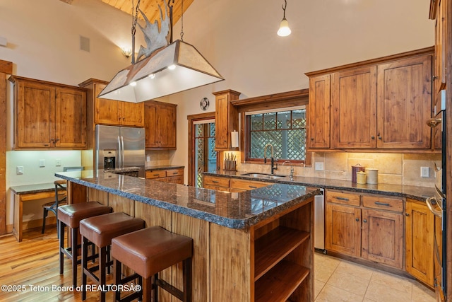 445 Aspen Ridge Trl, Alpine, WY 83128 - kitchen featuring stainless steel fridge with ice dispenser, high vaulted ceiling, open shelves, brown cabinetry, and decorative backsplash