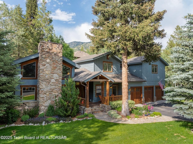 445 Aspen Ridge Trl, Alpine, WY 83128 - view of front facade with a garage, a chimney, asphalt driveway, a porch, and a front yard