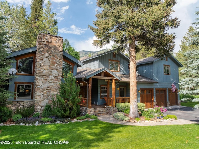 445 Aspen Ridge Trl, Alpine, WY 83128 - view of front of property with a garage, driveway, a porch, a front yard, and a chimney