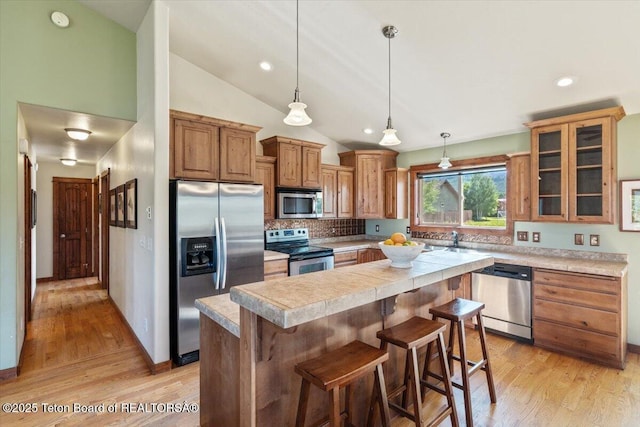 172 Brome Dr, Victor, ID 83455 - kitchen with appliances with stainless steel finishes, light countertops, light wood-type flooring, tasteful backsplash, and a center island