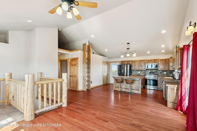 25 Neosha Trl, Boulder, WY 82923 - kitchen featuring appliances with stainless steel finishes, a center island, a breakfast bar area, vaulted ceiling, and light wood-style floors