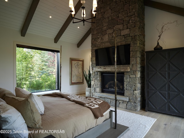 5060 W Eagle Rd, Wilson, WY 83014 - bedroom featuring wood finished floors, a chandelier, a stone fireplace, and wooden ceiling